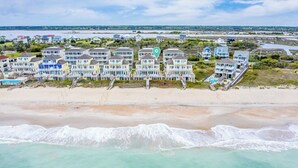 A coastal residential area with beachfront properties, including multi-story houses with balconies and a sandy beach. - Sea the Love by Topsail Realty (Sneads Ferry)