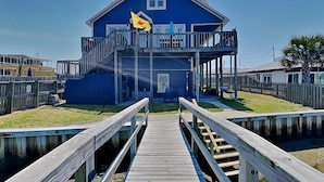 A blue house with a balcony, a wooden dock, and a flag.
