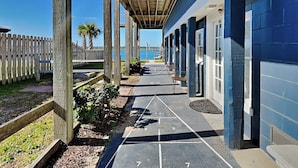 A covered walkway leading to a row of rooms with a view of the water.