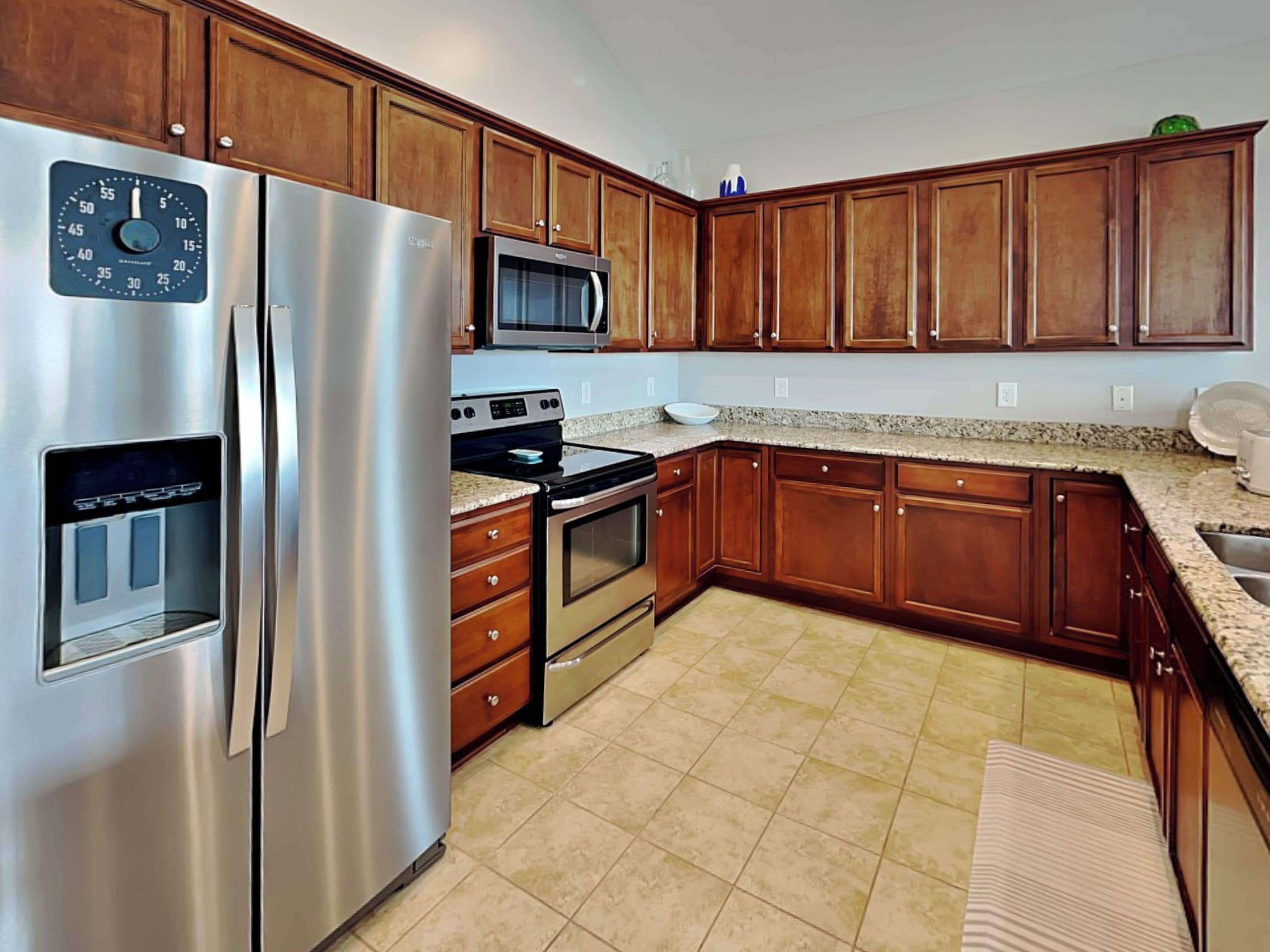 A kitchen with wooden cabinets, stainless steel appliances, a microwave, and granite countertops.
