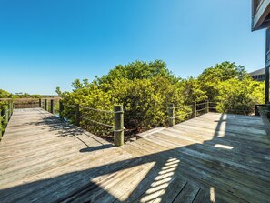 A wooden boardwalk leading to a building with a view of green foliage.