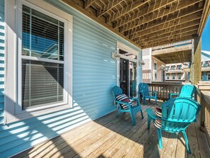 A covered porch with wooden flooring, two turquoise Adirondack chairs, and a small table.
