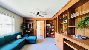 A modern living room with a blue sofa, wooden bookshelves, and a ceiling fan. - Sleeps 12/Mid-Century Cool/Minutes to Stadium (State College)