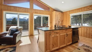 Una cocina amplia con armarios de madera, una isla central y grandes ventanales con vistas a las montañas.