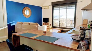 A modern living room with a blue accent wall, a round mirror, a sofa, and a dining area with a wooden table and chairs.