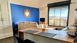 A modern kitchen with a blue accent wall, a round mirror, and a large window.