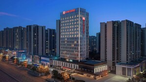 A modern hotel with a prominent sign, surrounded by high-rise buildings. - Hilton Garden Inn Leshan Shizhong (Leshan)