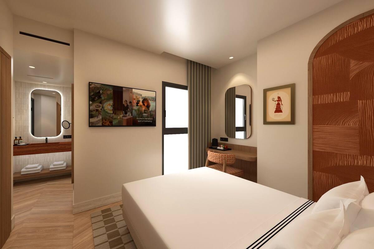 A modern hotel room with a large bed, a bathroom with a vanity, and a hallway leading to another room.