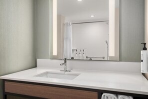 A modern bathroom with a large mirror, a sink, and a shower. - Hilton Garden Inn Perry (Perry)