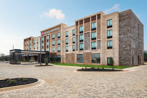 A Hilton Garden Inn with a brick facade, multiple windows, and a covered entrance area. - Hilton Garden Inn Perry (Perry)