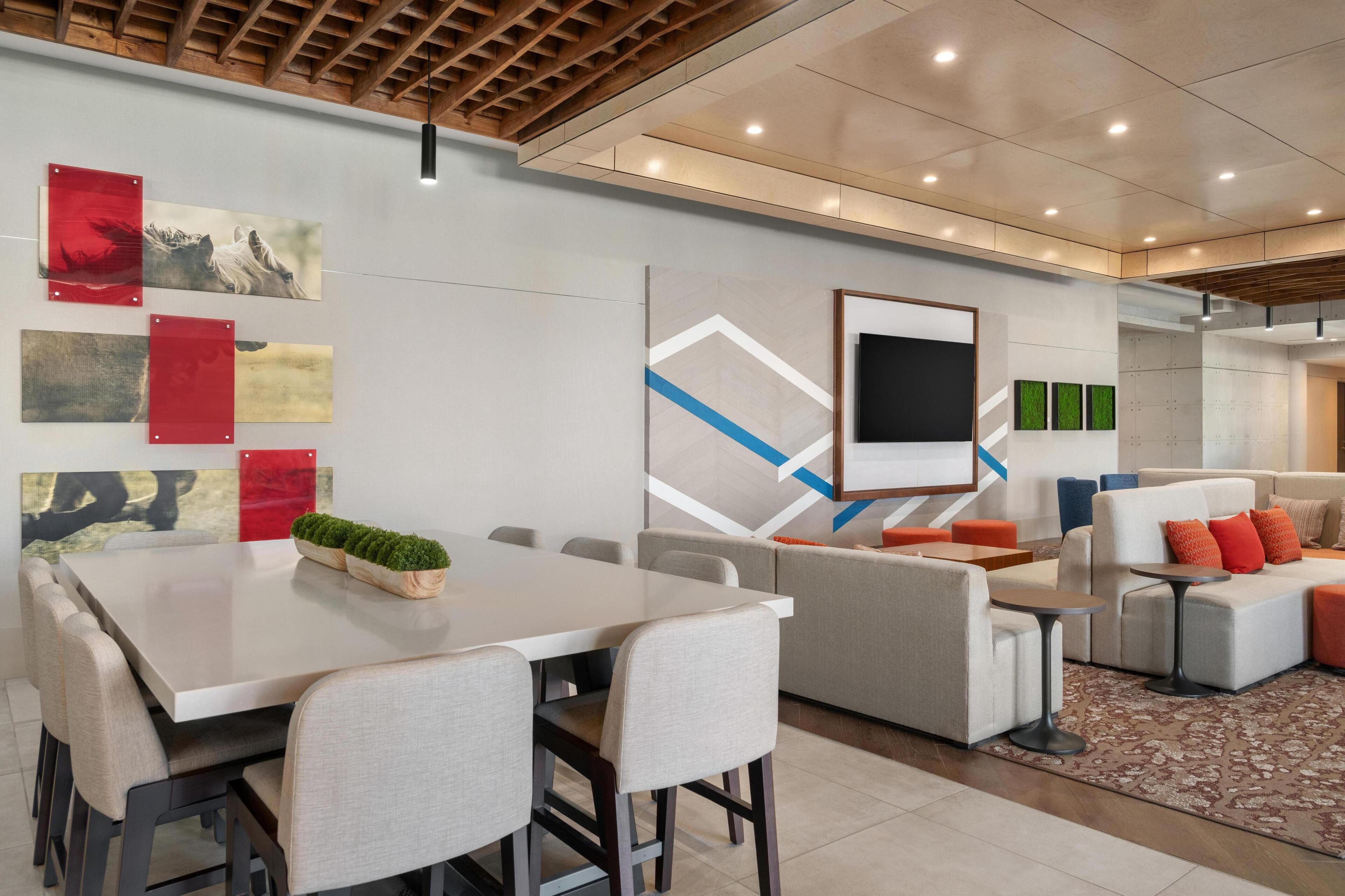 A modern conference room with a large table, chairs, a sofa, and a television.