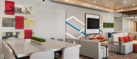 A modern conference room with a large table, chairs, a sofa, and a television.