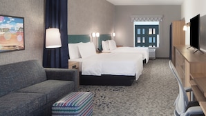 Une chambre d’hôtel avec un lit, un canapé, une télévision et un bureau.