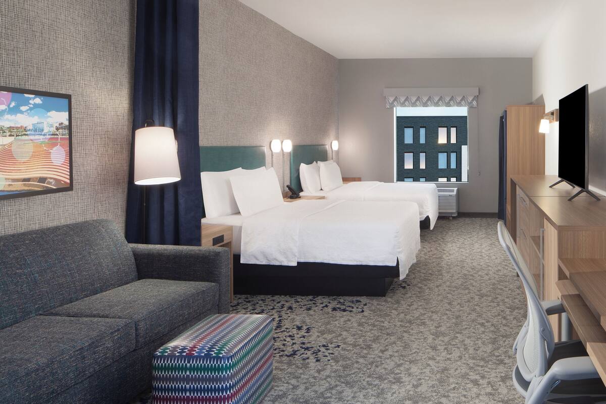 Una habitación de hotel con cama, sofá, televisor y escritorio.