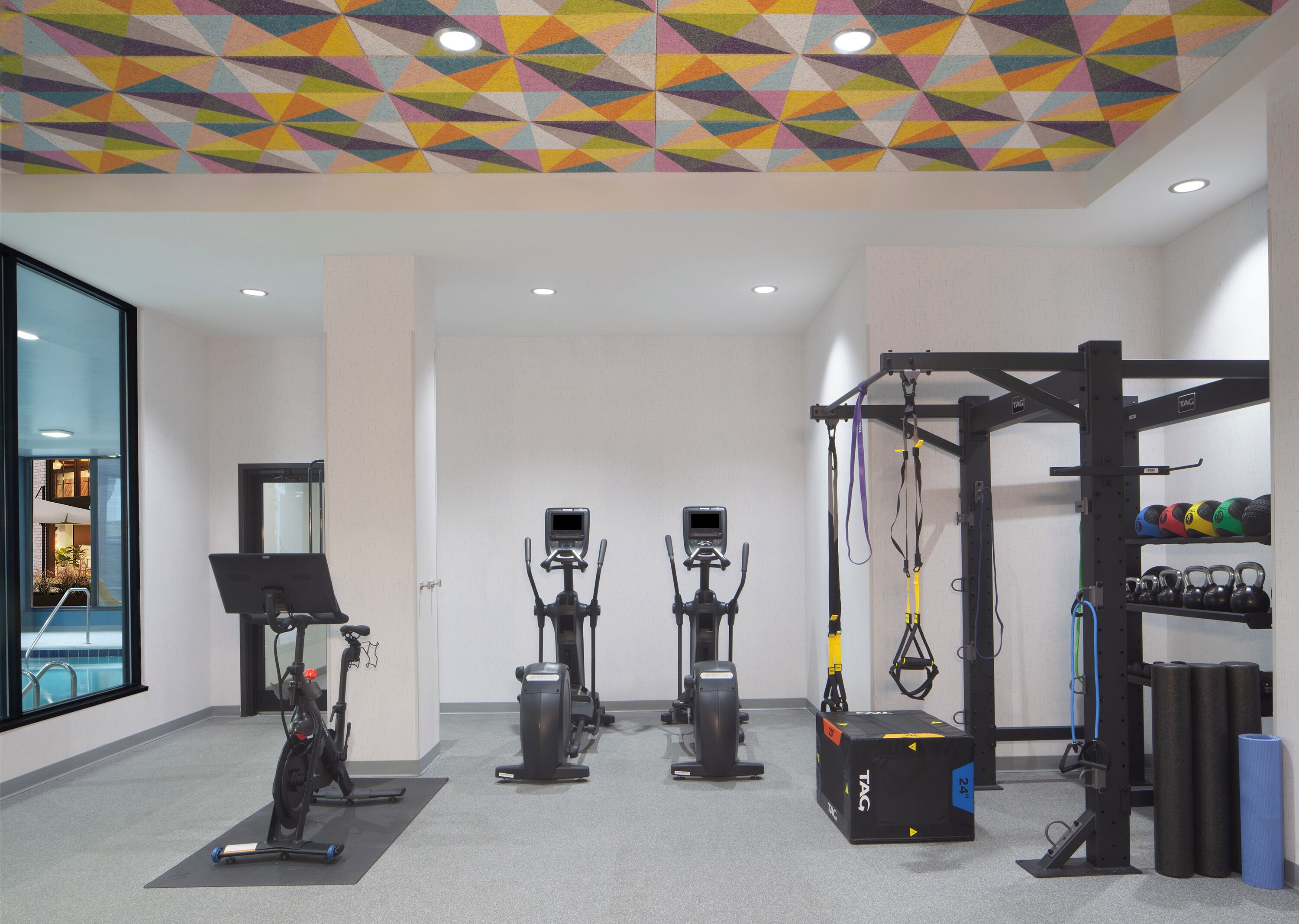 Un gimnasio con diferentes equipos de ejercicio, como bicicletas estáticas, cintas de correr y una zona de pesas.
