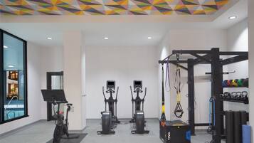 Un gimnasio con diferentes equipos de ejercicio, como bicicletas estáticas, cintas de correr y una zona de pesas.