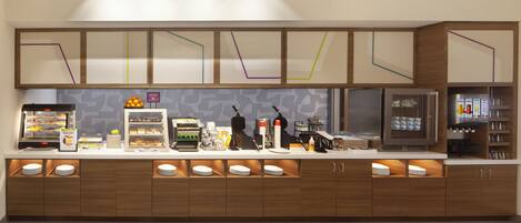 Un buffet-repas moderne en libre-service, proposant une variété d’aliments, une machine à café et un réfrigérateur.