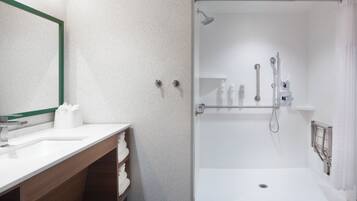 A modern bathroom with a white sink, wooden vanity, and a glass-enclosed shower area.