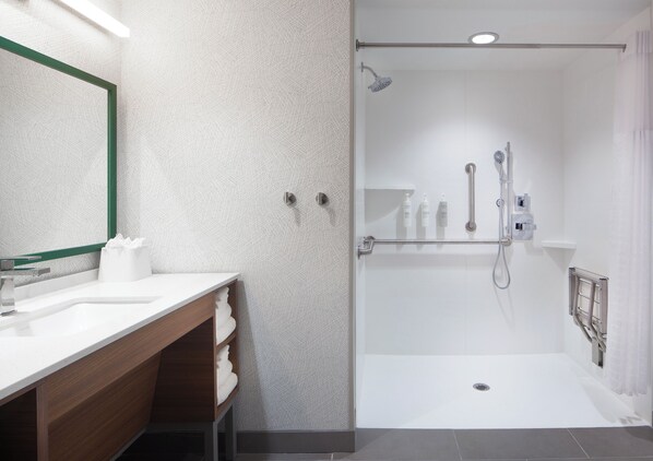 A modern bathroom with a white sink, wooden vanity, and a glass-enclosed shower area.