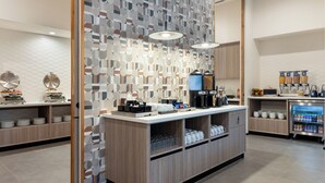 Un área de cocina moderna con un montaje tipo bufé, que incluye una estación de café y dispensadores refrigerados para bebidas.