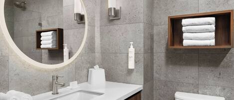 A bathroom with a white sink, a toilet, a mirror, and a towel rack.