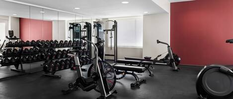 A gym with various exercise equipment, including dumbbells, a bench, and a treadmill.