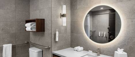 A modern bathroom with a toilet, sink, and mirror.