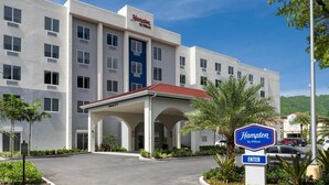 Un hotel Hampton by Hilton con fachada moderna, entrada cubierta y cielo despejado.