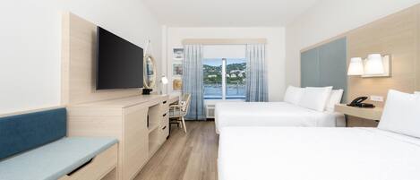 Une chambre d’hôtel avec un lit, un bureau, une chaise, une télévision et une fenêtre avec des rideaux.