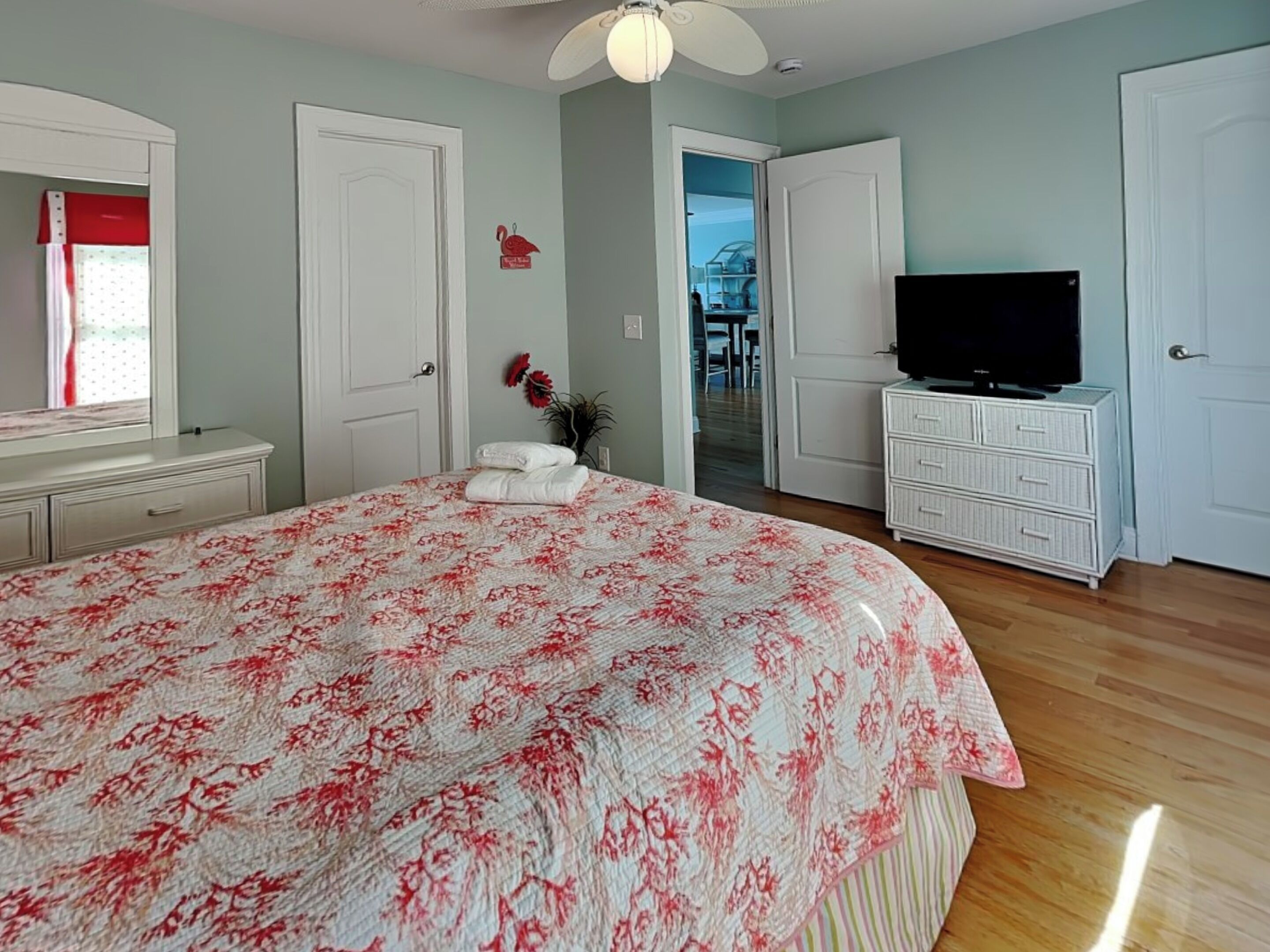 Une chambre à coucher avec un grand lit, une télévision, une commode et une porte donnant sur un balcon.