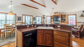 Una cocina amplia con armarios de madera, lavavajillas e isla grande con pileta.