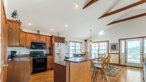 Una cocina con armarios de madera, una isla central y un comedor con sillas.