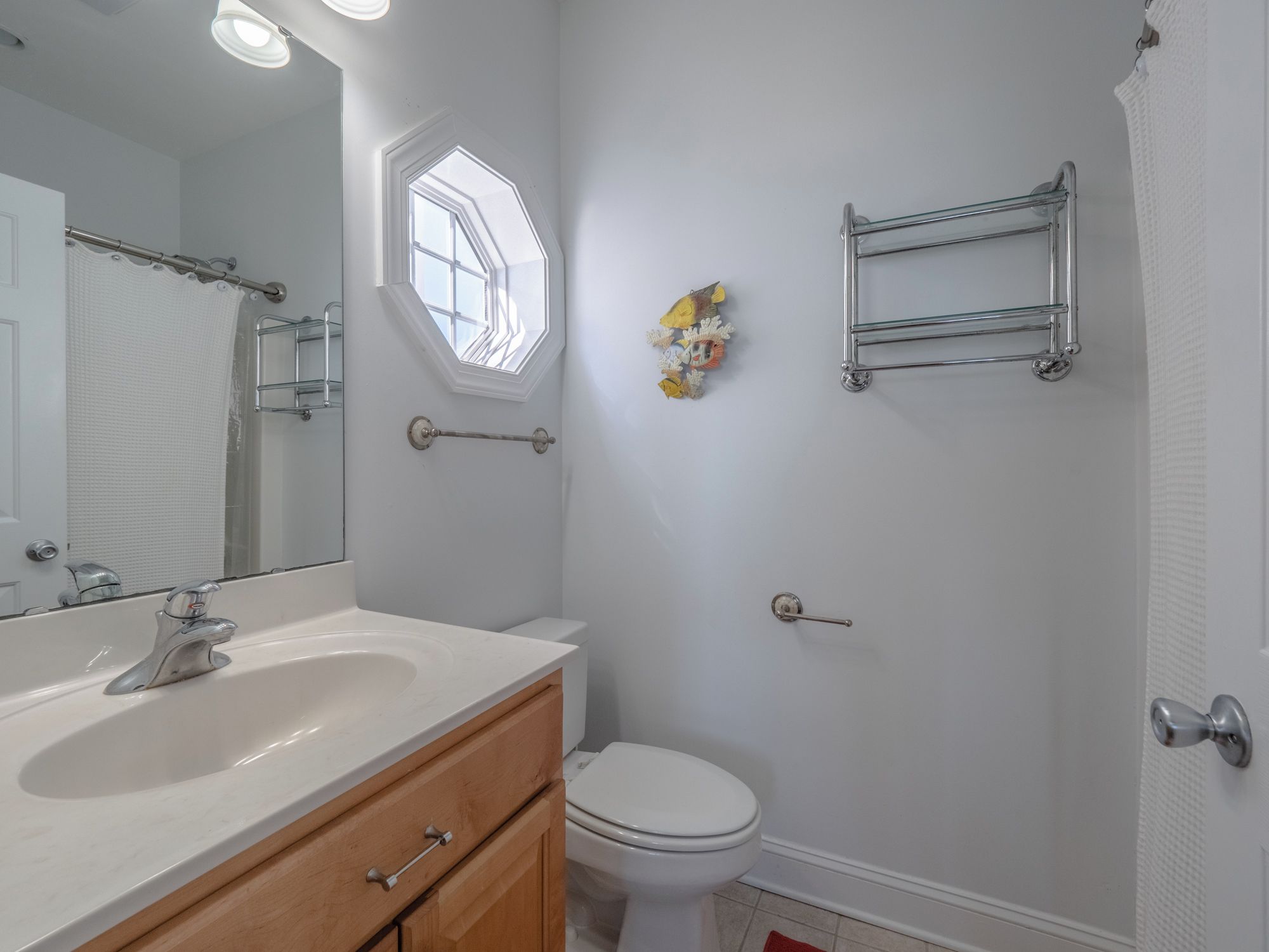 A bathroom with a white sink, a toilet, a shower area, and a window.