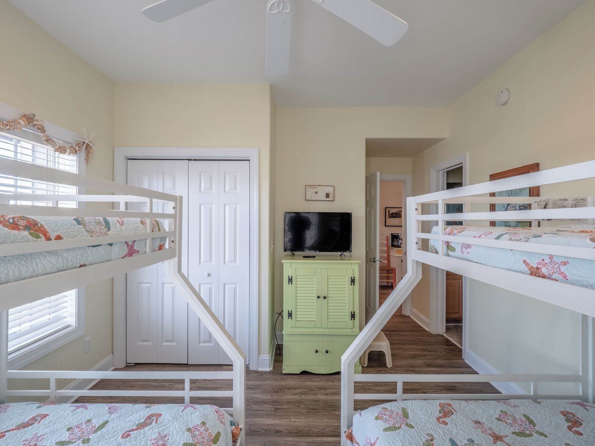 A child’s bedroom with bunk beds, a television, and a green cabinet.