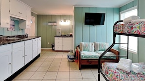 A compact room with a bunk bed, a kitchenette, and a television. - Shoo Fly by Carolina Retreats (Kure Beach)