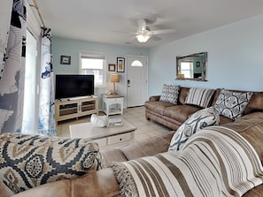A living room with a television, sofa, and a ceiling fan. - Shoo Fly by Carolina Retreats (Kure Beach)
