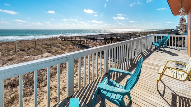 A wooden deck with a railing overlooking a beach and ocean. - Shoo Fly by Carolina Retreats (Kure Beach)