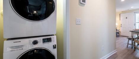 A laundry room with two stacked front-loading washing machines and a wall-mounted thermostat.