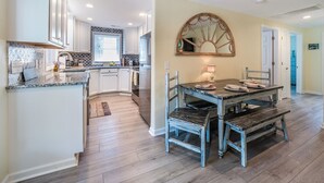 A modern kitchen with white cabinets, a granite countertop, and a built-in oven. - Ankers Away by Topsail Realty (Holly Ridge)