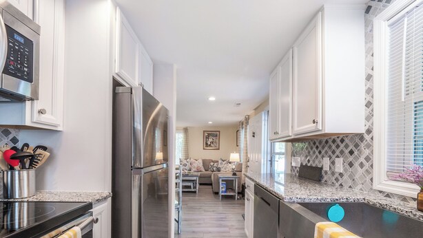 Una cucina moderna con elettrodomestici in acciaio inox, una zona pranzo con divano e tavolo, e vista sul soggiorno.
