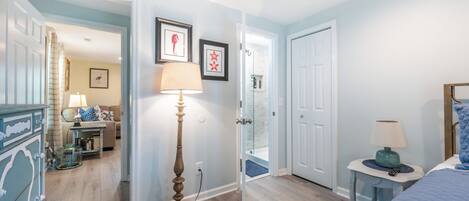 A bedroom with a bed, bedside tables, a lamp, and a door leading to a bathroom.