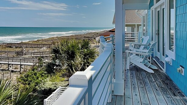 A beachfront property with a wooden deck and white railings overlooking the ocean. - A Shore Cure by Carolina Retreats (Kure Beach)