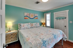 Une chambre à coucher avec un lit, deux tables de chevet, une porte et une fenêtre.