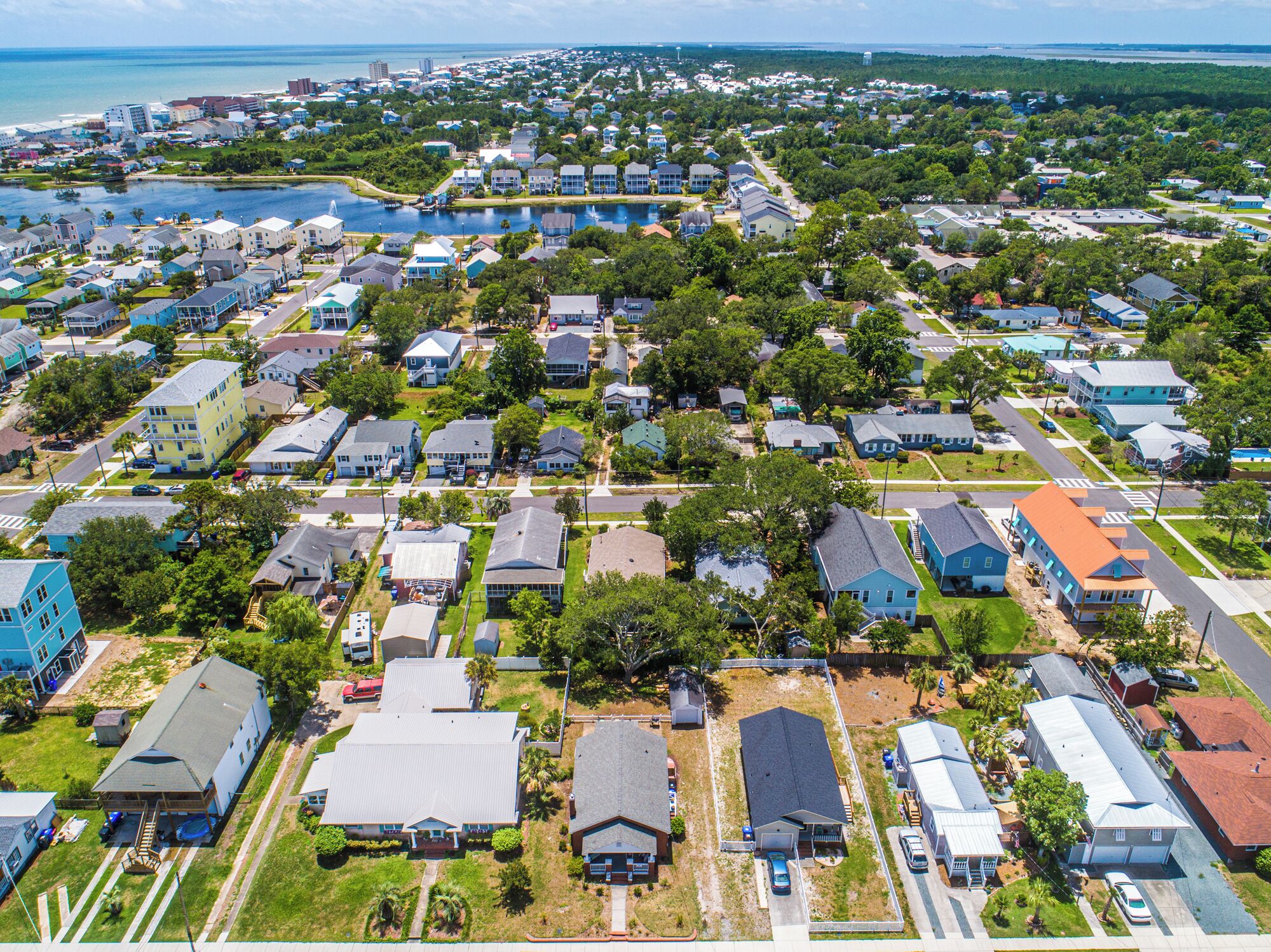 An aerial view of a residential area with houses, streets, and a body of water in the background.