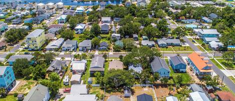 An aerial view of a residential area with houses, streets, and a body of water in the background.