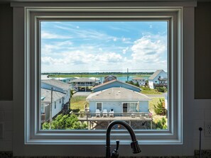 A window with a view of a residential area, including houses and a body of water. - Next to Sea Gallery by Topsail Realty (Holly Ridge)