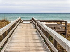 A wooden boardwalk leading to a beach with a clear view of the ocean. - Dooley's Place by Carolina Retreats (Carolina Beach)