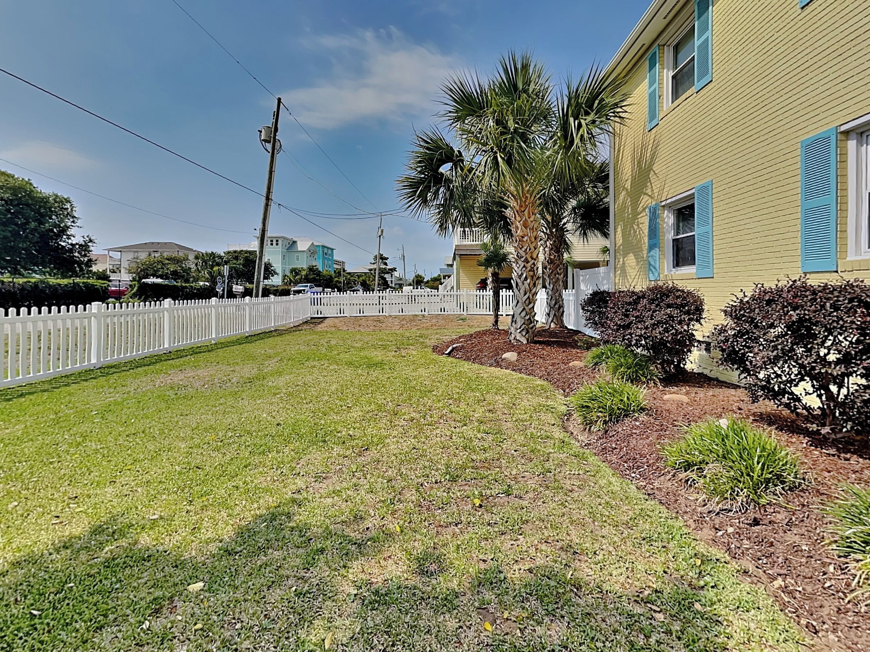A residential property with a well-maintained lawn, a white picket fence, and a house with blue shutters.