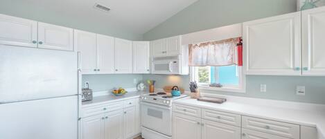 A kitchen with white cabinets, a microwave, a stove, and a ceiling fan.