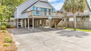 A two-story house with a balcony and a sign that reads "Beachy." - Just Beachy Spartanburg by Carolina Retreats (Carolina Beach)